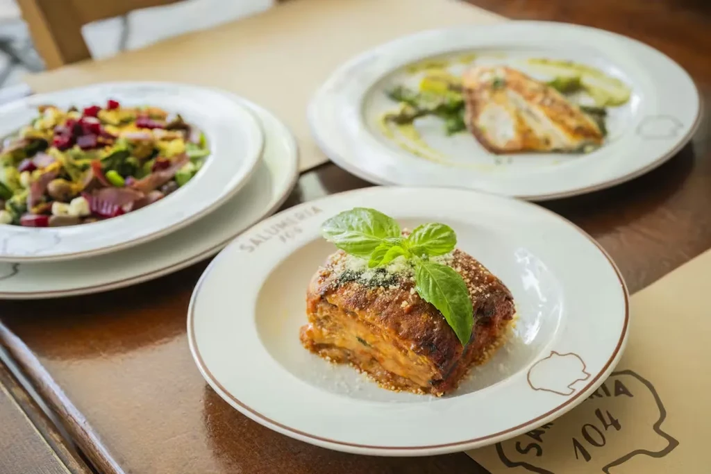 Salumeria's baked pasta, colorful salad, and seared protein.