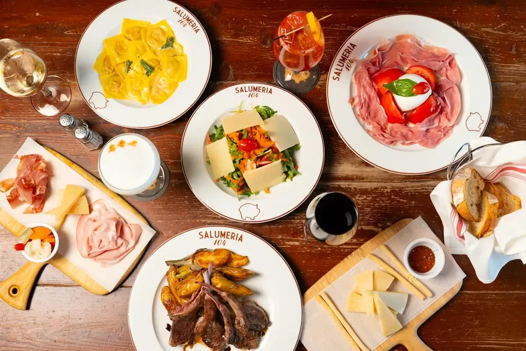 Various Italian dishes and drinks on a rustic dark wooden table.