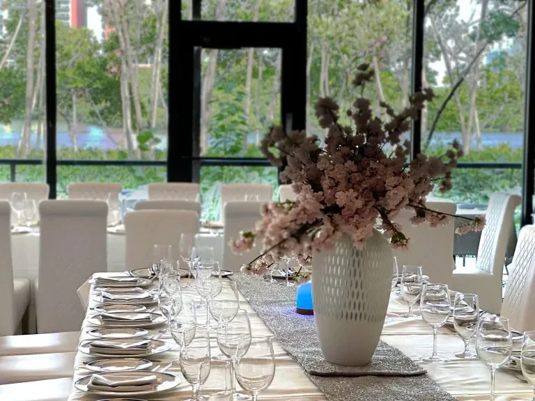 Meticulously set dining table with pink cherry blossoms and scenic view.