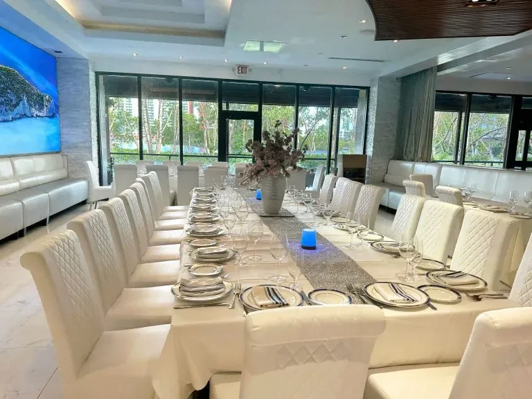 Elegant restaurant dining room with a long set table and ocean art.