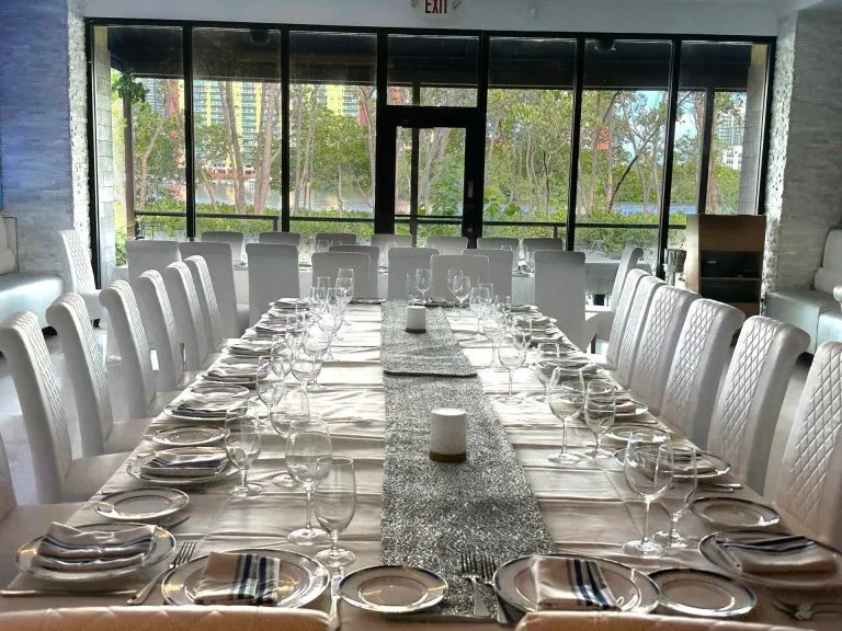 Elegant dining table set for a large group, overlooking green landscape.