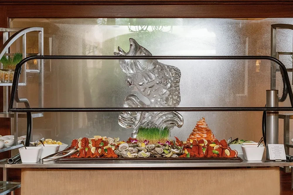 Seafood buffet with lobster, oysters, shrimp, and a fish ice sculpture.