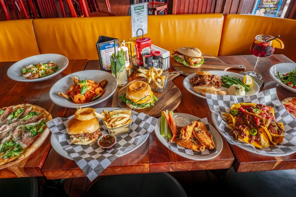Diverse dishes and drinks on a dark wooden restaurant table.