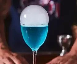 Vibrant blue cocktail with a large, spherical smoke bubble.