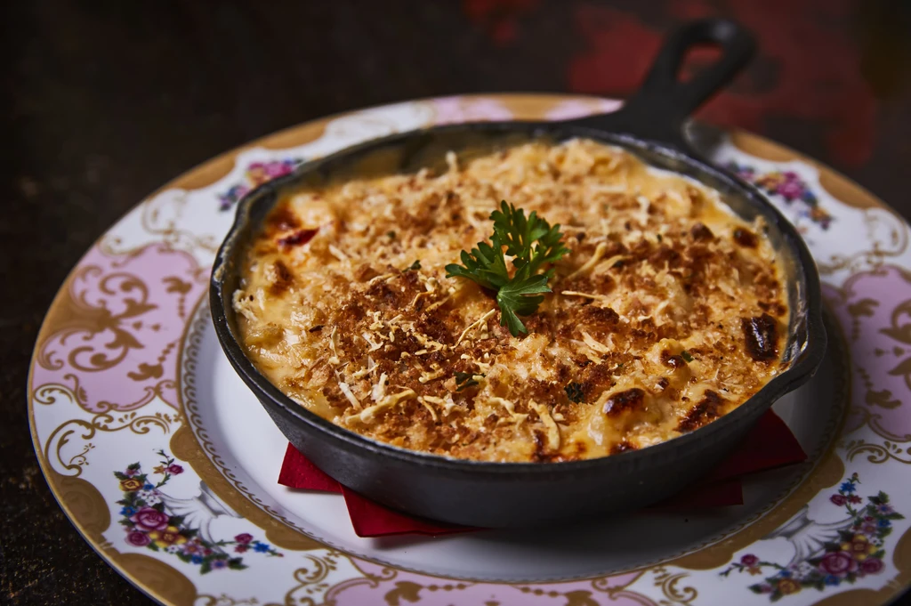 Golden gratin in a skillet with parsley on a decorative plate.