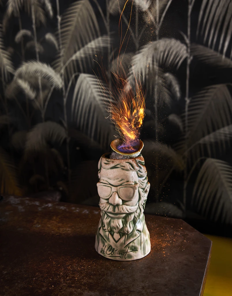Green ceramic tiki mug bust with beard, sunglasses, and active flames.