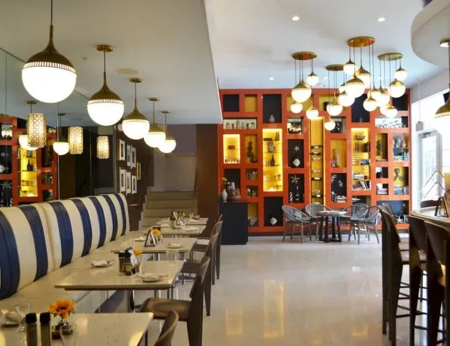 Modern restaurant interior with blue striped banquette and illuminated shelves.