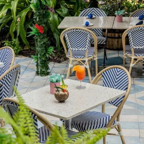 Outdoor tropical dining area, cocktails, rattan chairs with chevron fabric.