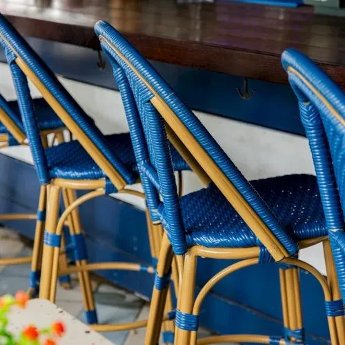 Three light brown and royal blue woven bar stools.