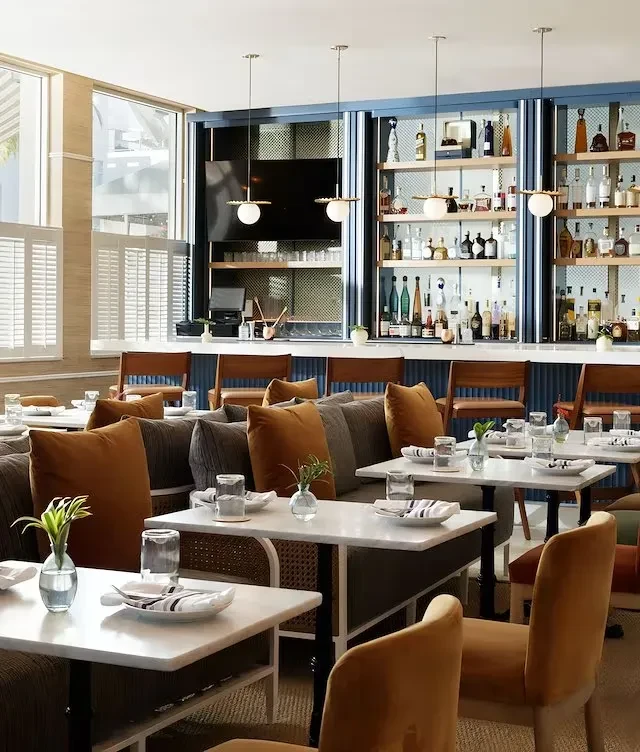 Modern restaurant interior with marble tables and a blue-paneled bar.