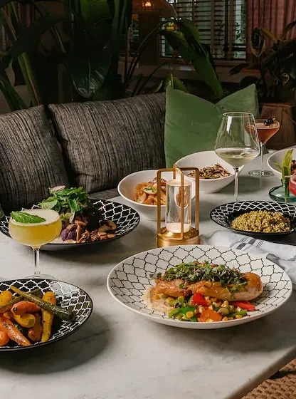 Meticulously plated dishes and drinks on a marble table in a restaurant.