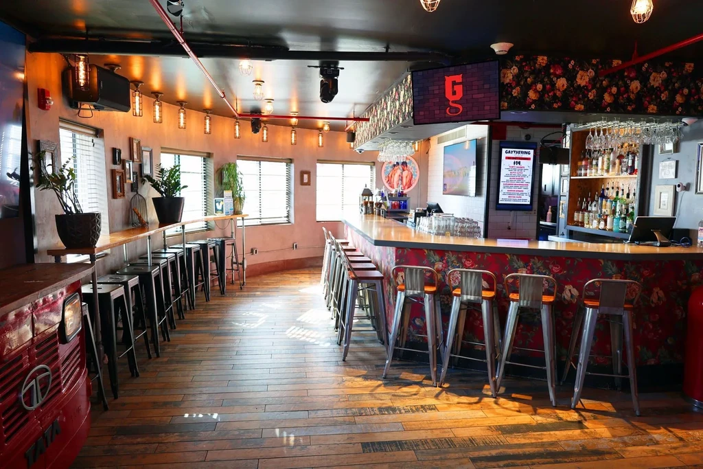 Empty modern bar interior with a red floral counter and TVs.