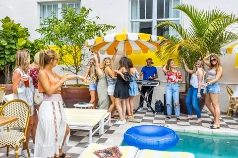 People enjoy drinks and music at a vibrant poolside patio party.