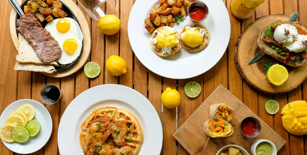 Vibrant breakfast and brunch spread with eggs, waffles, steak, and burritos.