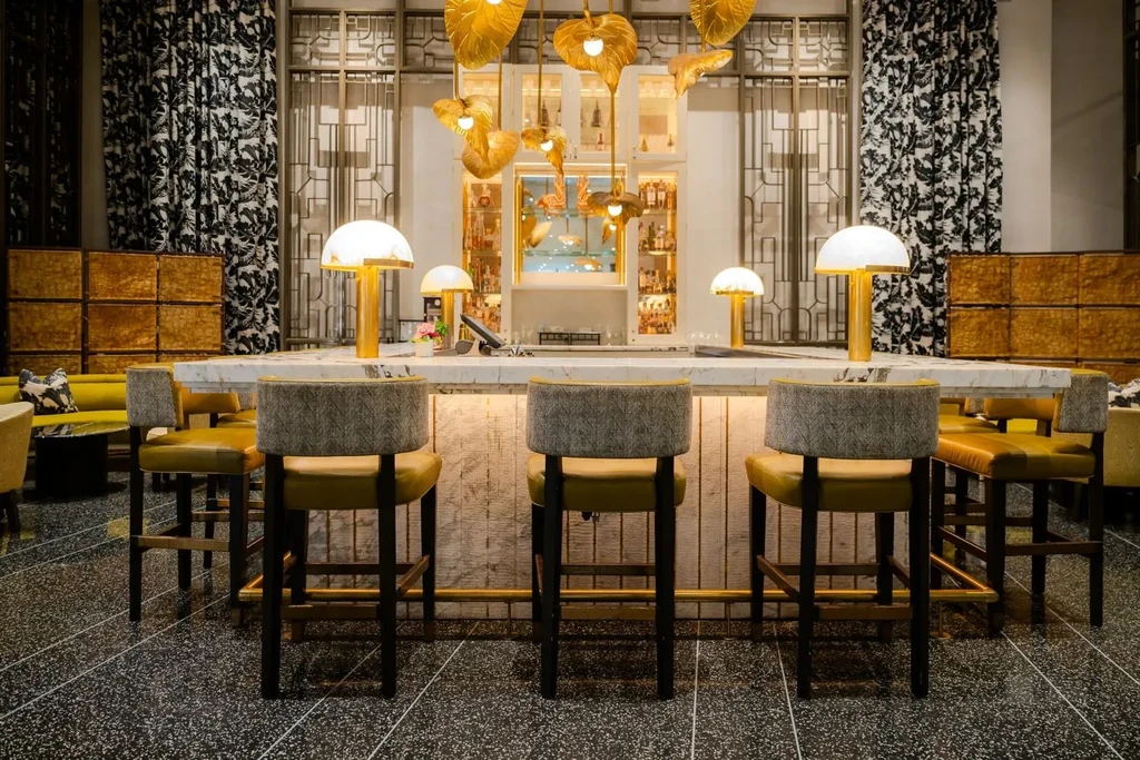 Sophisticated bar with illuminated white marble counter and gold leaf chandeliers.