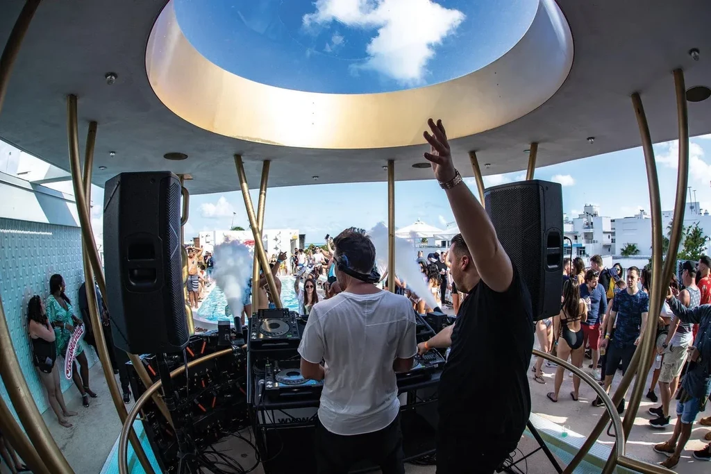 DJs engaging a crowd at a vibrant, open-air pool party.