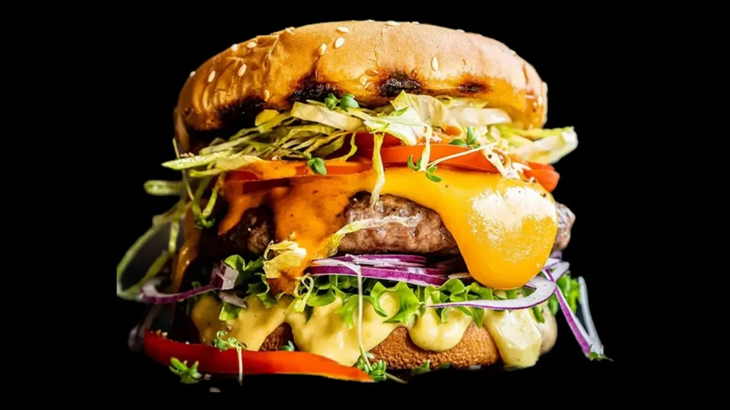 Close-up of a stacked gourmet burger with beef, cheese, and vegetables.