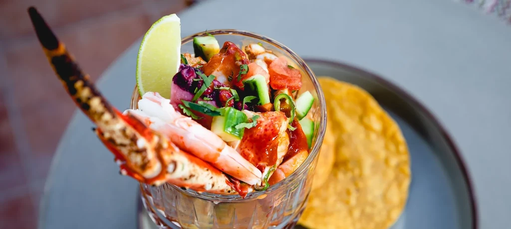 Vibrant seafood cocktail with shrimp, crab, colorful vegetables, lime, and tostada.