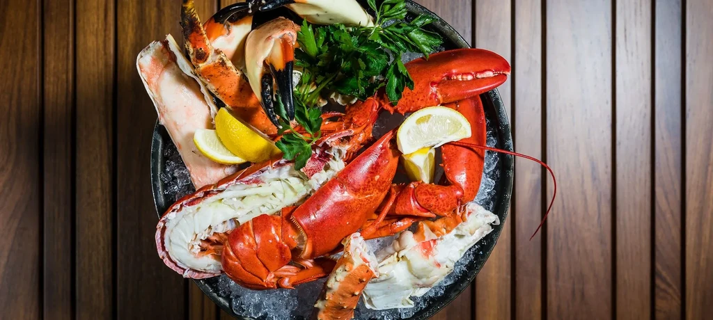 Cooked lobster and crab claws on ice with lemon and parsley.