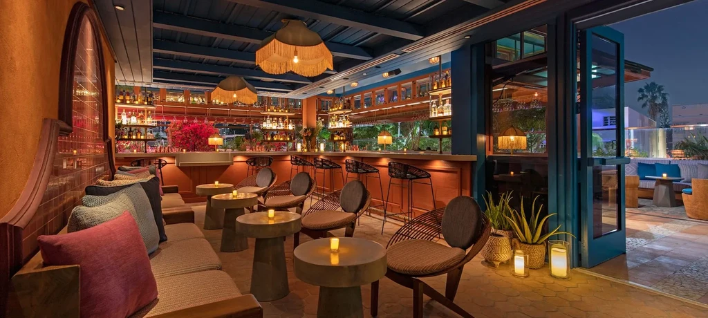 Upscale bar with terracotta walls, warm lighting, and outdoor patio.