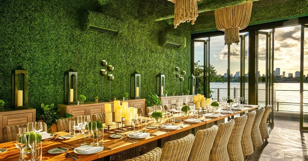 Lush green restaurant interior, elegant table, and sunset city skyline view.