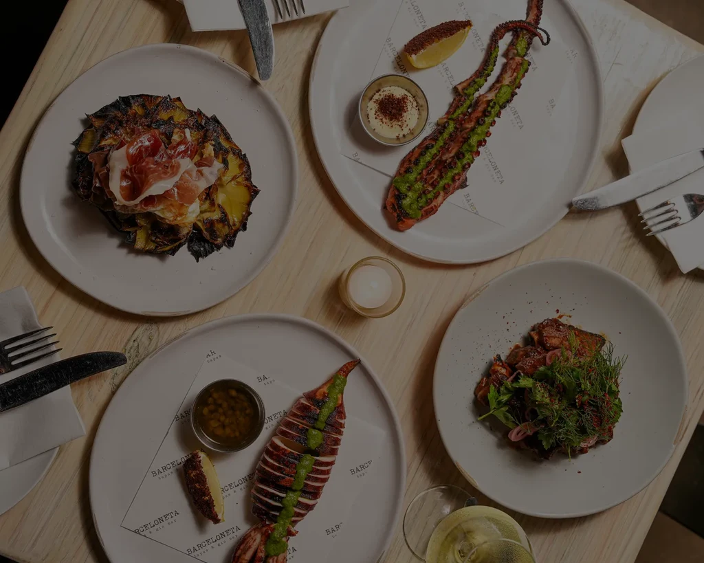 Overhead view: Artfully presented grilled tapas dishes on a wooden table.