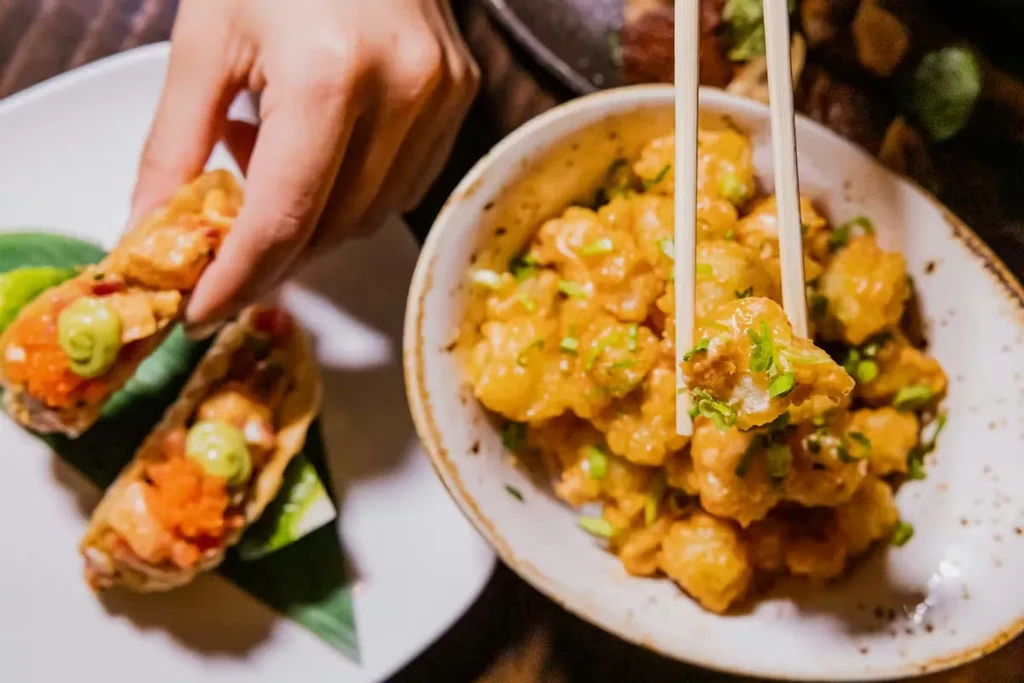 Close-up: Two restaurant dishes, crispy bites and sauced fried chicken/shrimp.