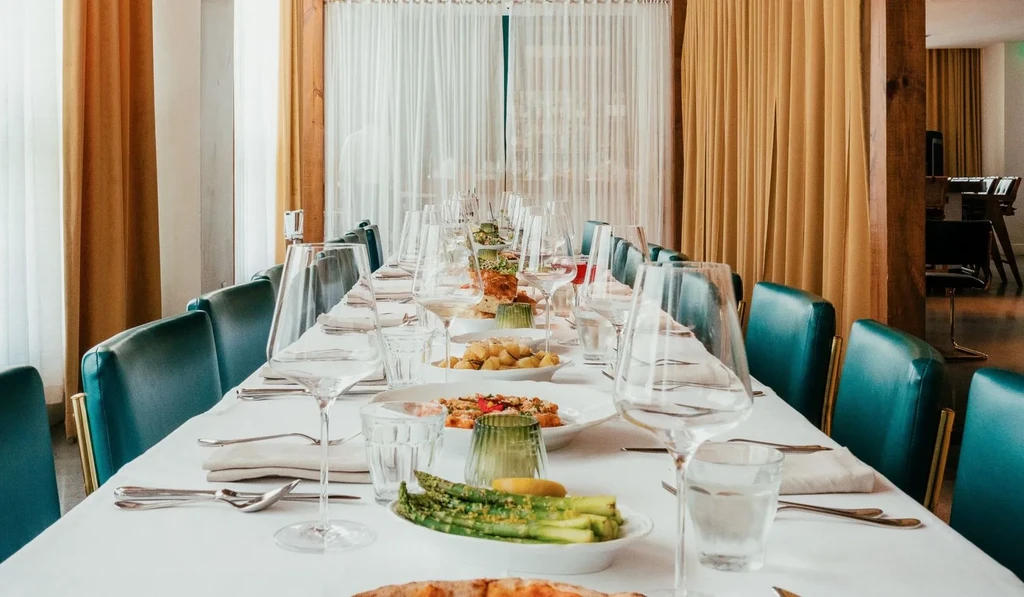 Modern dining table meticulously set with food and elegant green chairs.