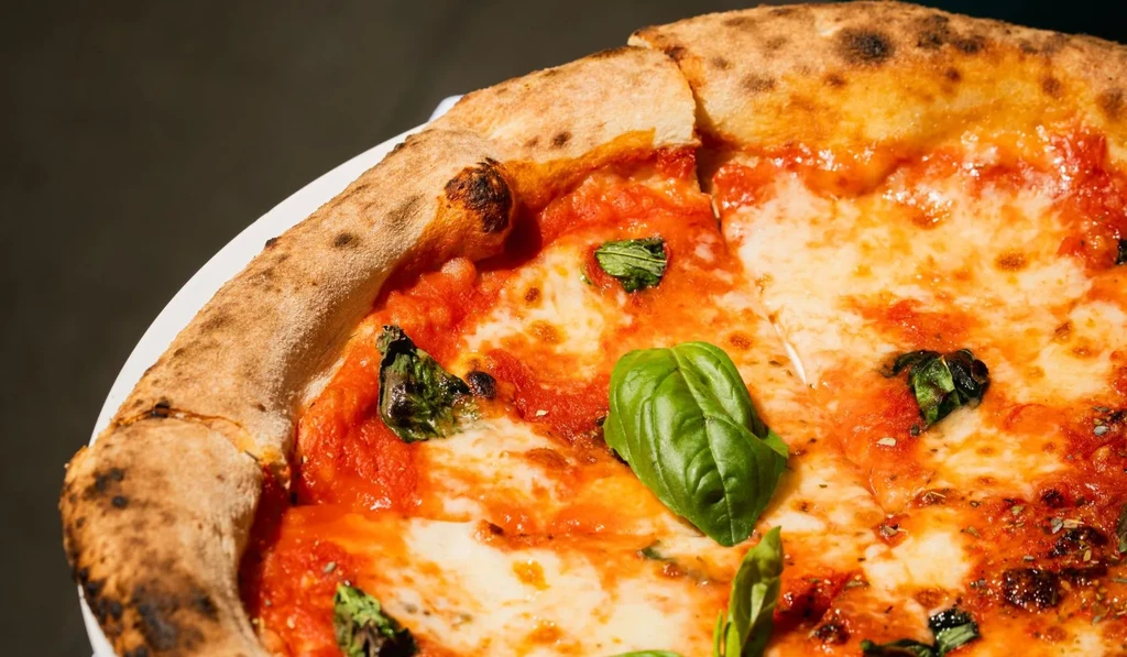 Neapolitan Margherita pizza with charred crust, melted mozzarella, and basil.