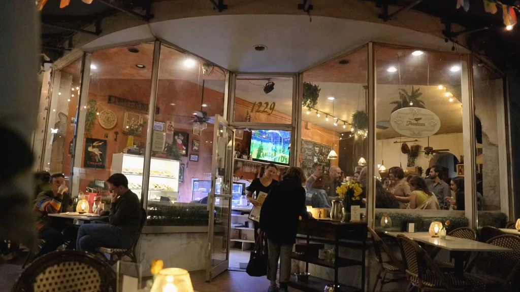 Nighttime view of a bustling restaurant with warm lighting and outdoor seating.