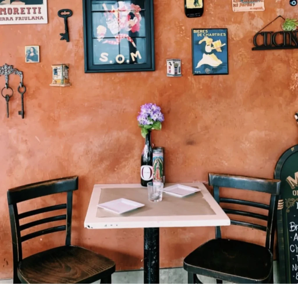 Cozy restaurant table for two against a decorated terracotta wall.