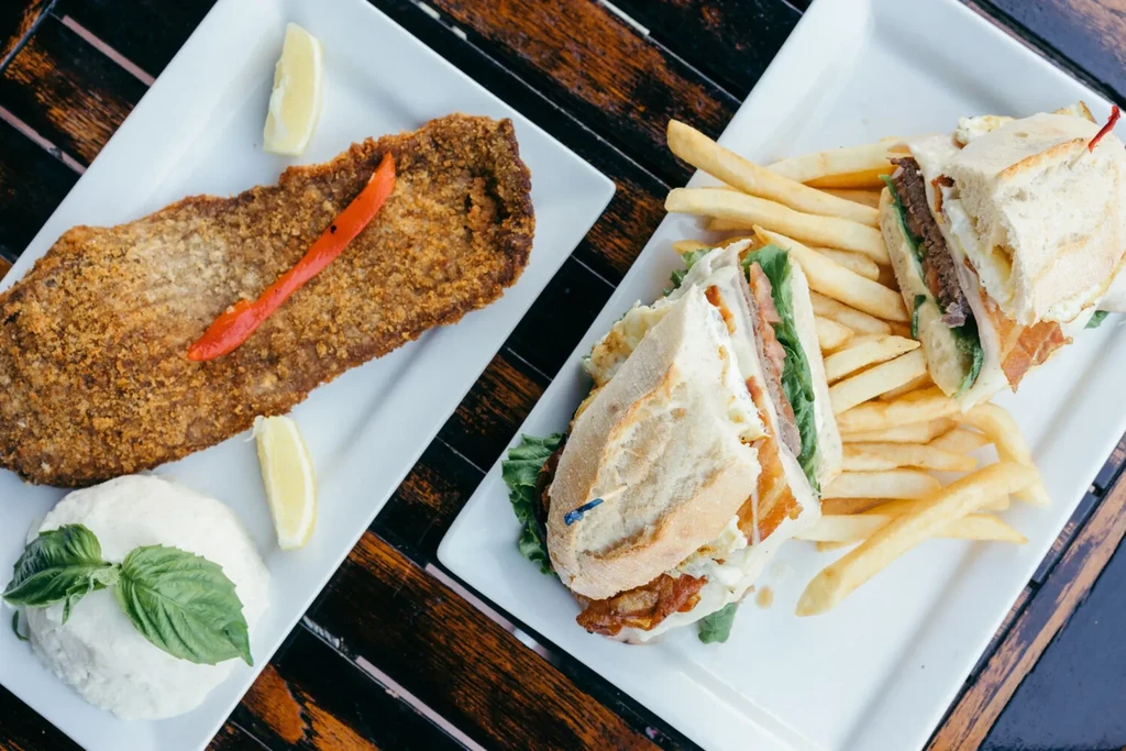 Overhead view: Breaded cutlet, creamy side, and a sandwich with fries.