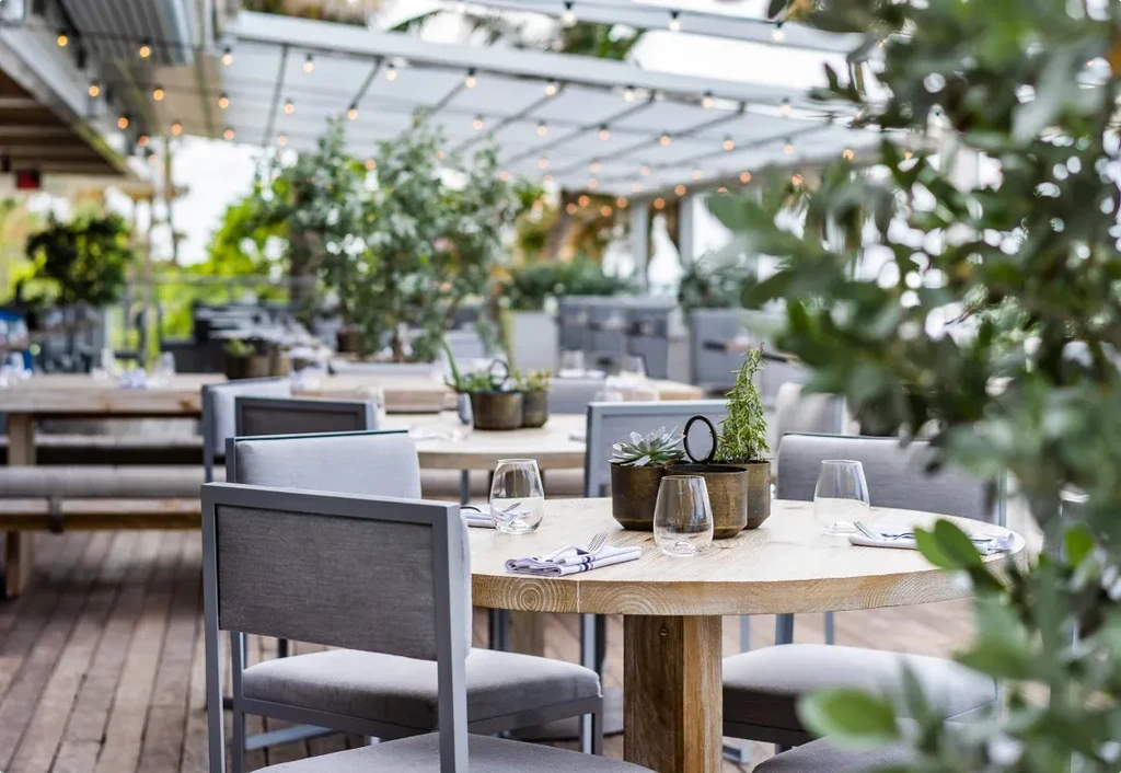 Outdoor restaurant patio with set tables, modern chairs, and string lights.