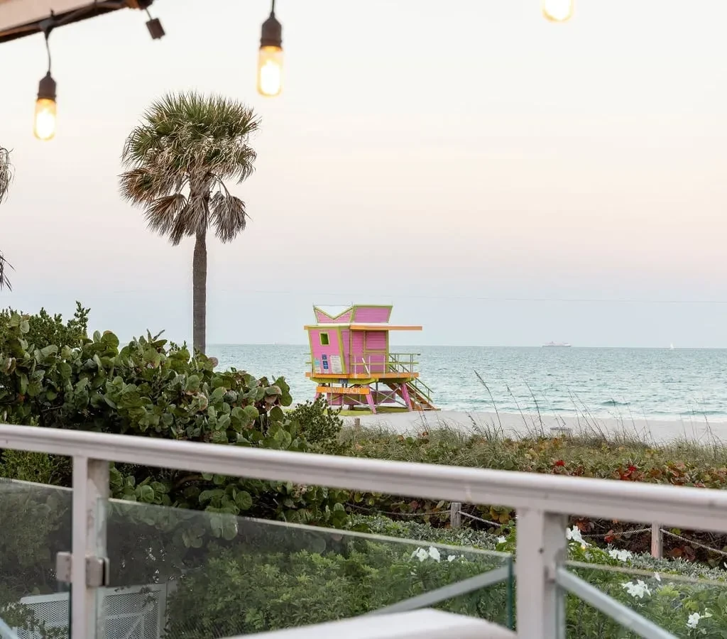 Elevated view of a pink and green lifeguard tower and beach at dusk.