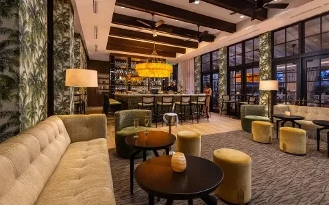 Upscale lounge interior with plush seating, bar, and palm tree wallpaper.