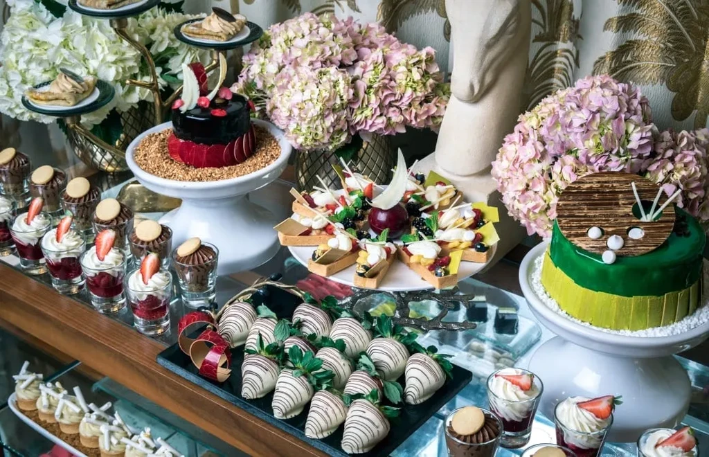Luxurious dessert buffet with cakes, tarts, and chocolate-covered strawberries.