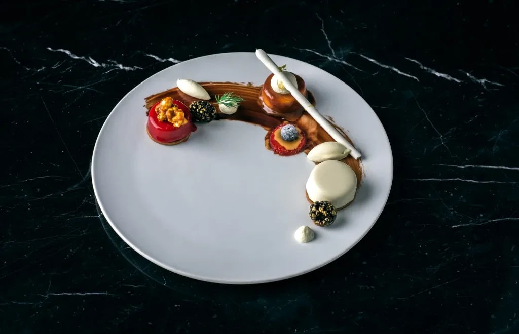 Artistically plated gourmet dessert with various components on dark marble.