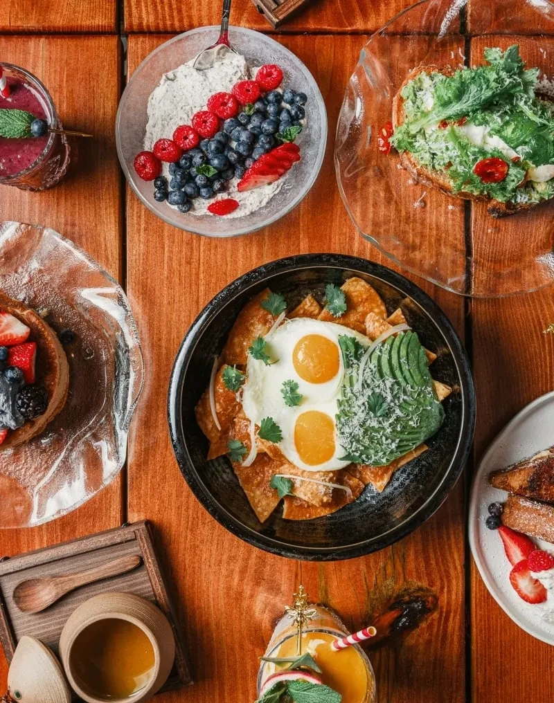 Flat lay of diverse breakfast and brunch dishes and drinks on wood.