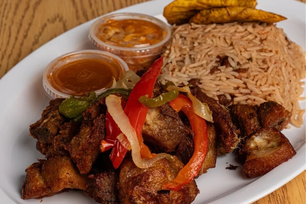 Colorful hearty meal of meat, vegetables, rice, plantains, and sauces.