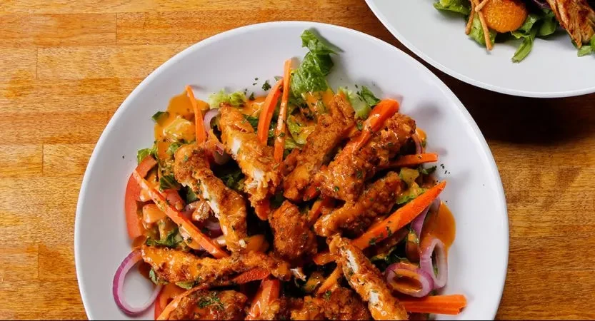 Top-down view of a large fried chicken salad with creamy dressing.