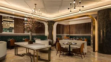 Elegant restaurant interior with green booths, wood paneling, and golden accents.