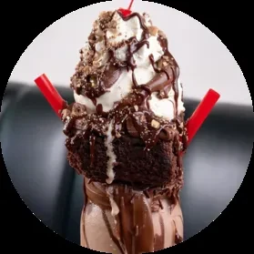 Elaborate chocolate milkshake with brownie, whipped cream, cherry, and toppings.