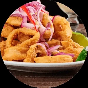 Piled golden fried seafood with red onions and lime wedges.