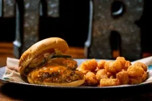 Melted cheese burger with savory sauce and golden tater tots.