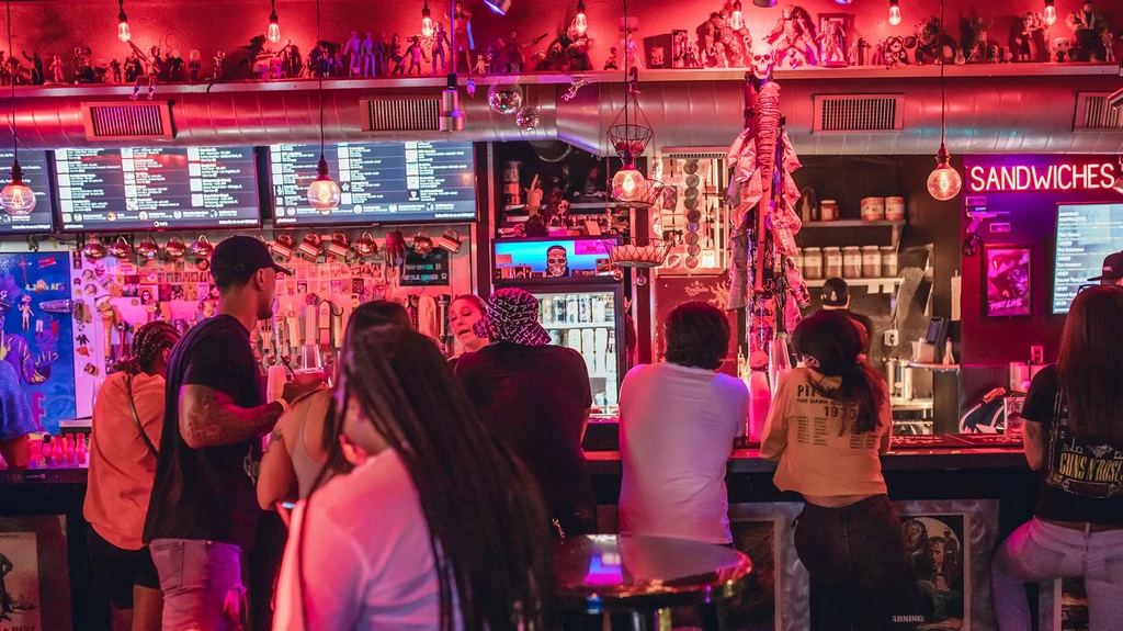 Bustling bar lit in red, decorated with skulls and action figures.