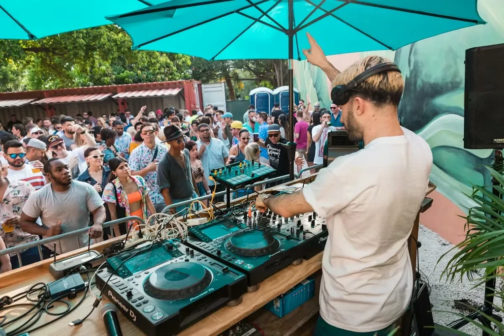 Energetic outdoor music event with a DJ mixing for a large crowd.