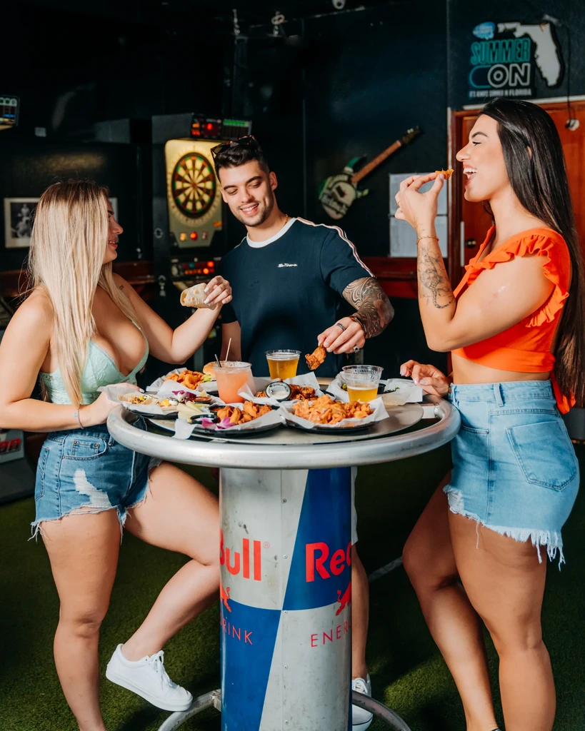 Two women, one man, dining casually at a Red Bull branded table.