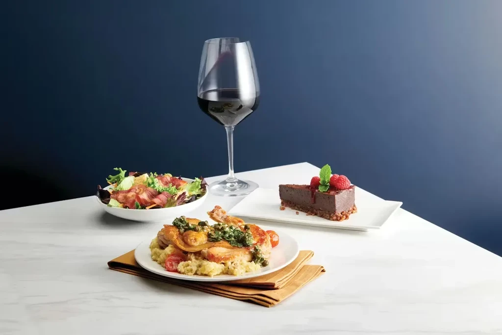 Culinary spread with chicken, green salad, red wine, and chocolate cake.