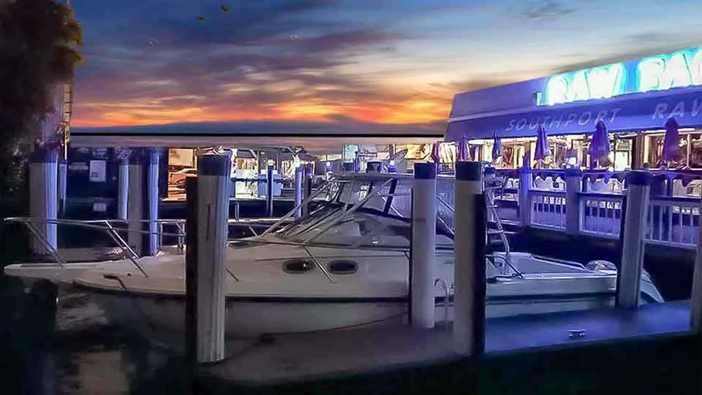 Vibrant sunset over waterfront restaurant and docked boats.