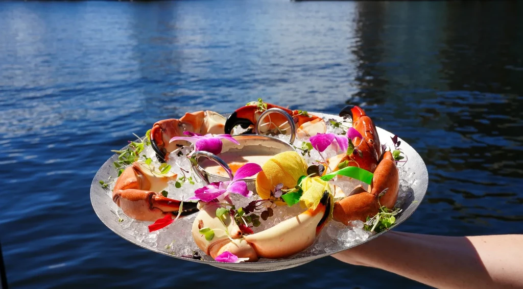 Silver platter of chilled crab claws on ice, with purple orchids.